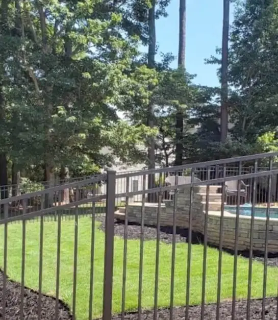 Black aluminum fence surrounding a backyard pool