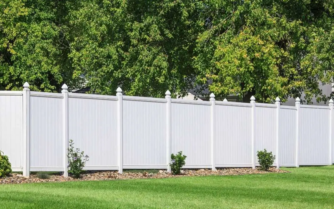 White vinyl privacy fence along a green backyard lawn